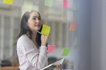 Business female employee with many conflicting priorities arranging sticky notes commenting and...