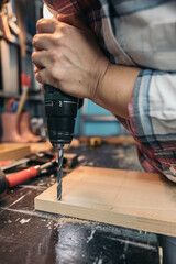 Woman drilling a hole in the wood with a drill
