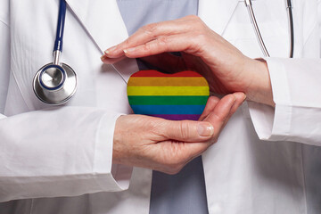Doctor holding heart with flag of LGBT. Healthcare, charity, insurance and medicine concept