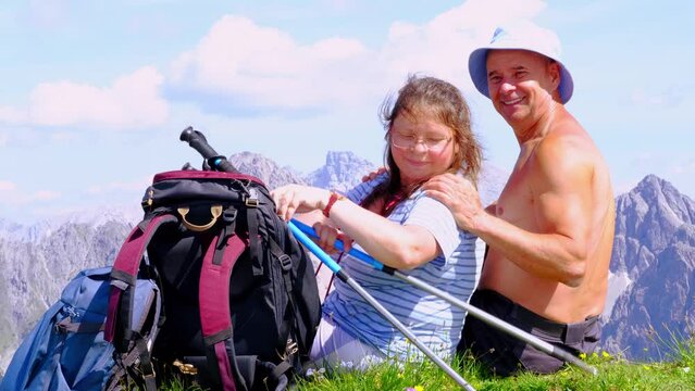 backpacks, mature tanned man and woman sitting on top mountain, Seefeld in Tirol, rests, enjoys beauty nature, extreme lifestyle of people, mountaineering, via ferrata in mountains, life insurance