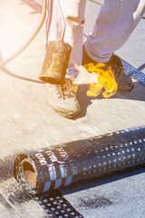 Roll roofing Installation with propane blowtorch during construction works