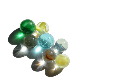 seven marbles with bright light reflecting through colorful glass with no background