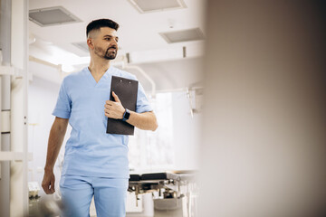 Naklejka na ściany i meble Male doctor working on laptop at the hospital