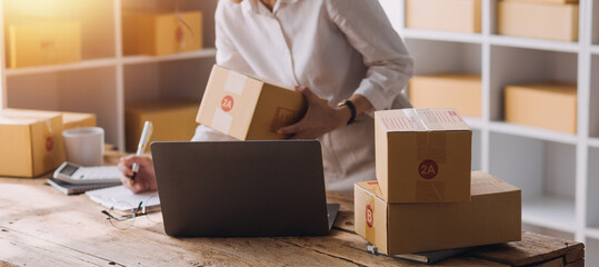 Startup SME small business entrepreneur of freelance Asian woman using a laptop with box Cheerful...