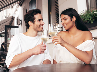 Smiling beautiful woman and her handsome boyfriend. Happy cheerful family. Sexy couple cheering with glasses of red wine at their date in restaurant. Drinking alcohol at veranda cafe