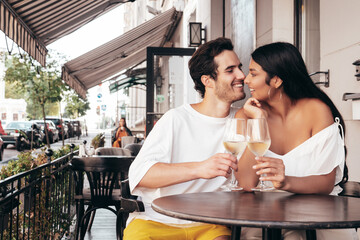 Smiling beautiful woman and her handsome boyfriend. Happy cheerful family. Sexy couple cheering with glasses of red wine at their date in restaurant. Drinking alcohol at veranda cafe