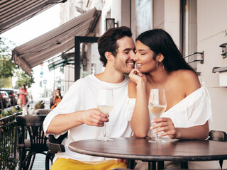 Smiling beautiful woman and her handsome boyfriend. Happy cheerful family. Sexy couple cheering with glasses of red wine at their date in restaurant. Drinking alcohol at veranda cafe