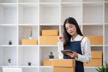 Fototapeta na wymiar Startup small business entrepreneur SME, asian woman packing cloth in box. Portrait young Asian small business owner home office, online sell marketing delivery, SME e-commerce telemarketing concept.