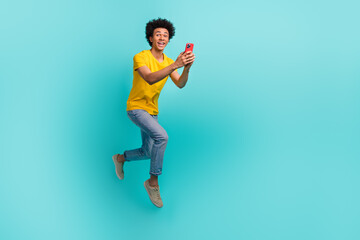 Fototapeta na wymiar Full length photo of excited active man jumping rush use smart phone empty space isolated on teal color background
