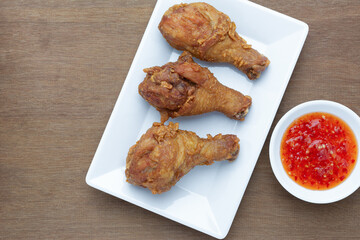 deep fried chicken drumstick in a white plate serve with sweet and spicy sauce on wooden table, top view.  homemade style food concept.