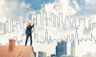 Man architect draw silhouette of modern city on blue sky. Mixed