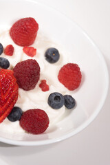 uno yogurt greco con frutti rossi, lamponi fragole e mirtilli in uno yogurt - obrazy, fototapety, plakaty