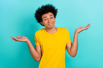 Portrait of confused funny guy afro hairdo wear yellow t-shirt shrugging shoulders has no idea...