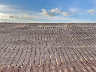Pattern of tire treads on mound of dirt at the edge of a suburban construction site near sunset in west central Florida