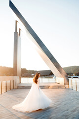 Obraz premium A beautiful bride in a long white dress against the background of the sunset
