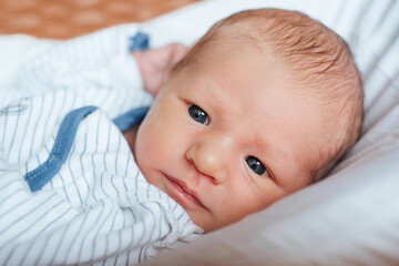 Portrait of pensive newborn baby on the bed at home