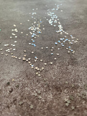 Silver star shaped glitter sparkles shining on marble background in the sun with shadows. Background. Close-up.