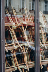 Fototapeta na wymiar Typical Parisian wicker chairs stacked one on top of the other in the windows of a closed restaurant