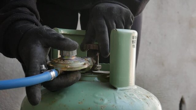 LPG cylinder connection with pressure regulator. close-up of a technician connecting a gas cylinder. pvc pipe. bottle sealed and ready to use.