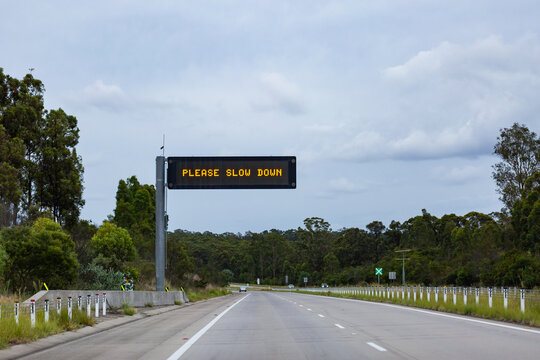Pleas slow down digital road sign above highway in NSW