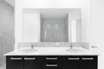 A modern bathroom with a black cabinet, marble countertop, and two showers with marble subway tile...