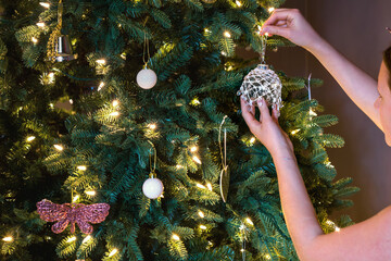 young teen hanging pretty ornament on xmas tree