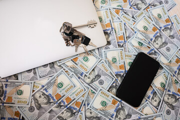 Dollar money with keys, laptop and phone background.