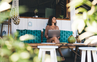 Contemplative female freelancer with digital netbook device thoughtful looking away thinking about...