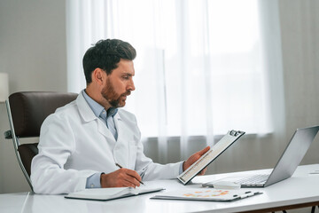 Fototapeta premium Reading the document. Doctor in formal clothes is working in the cabinet