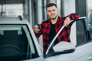 Handsome man choosing car in a car showroom