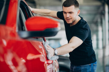 Young man polishing his car with rag