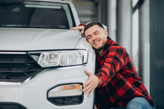 Man hugging a car in a car showroom