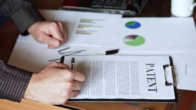 A man signs a patent document. Copyright registration. Patent law. Business