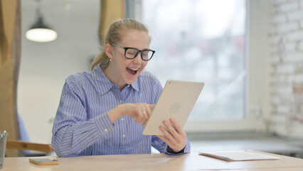 Young Woman Celebrating Success on Tablet at Work