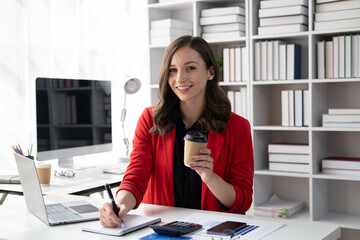 Young professional businesswoman working on her project while holding a coffee cup.