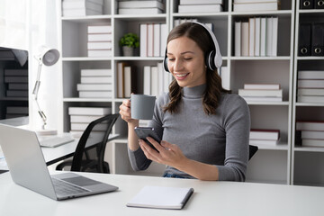 Elegent young businesswoman drinking coffee while sitting at her office desk.