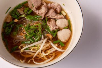 Noodles with pork and pork balls with soup Thai style in white bowl