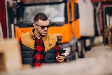 Handsome man truck driver standing by the truck and using phone