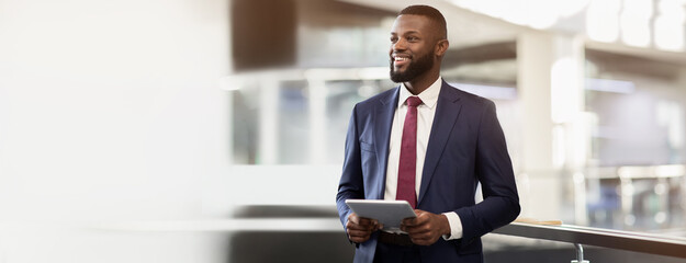 Smiling handsome confident african american millennial businessman ceo with beard use tablet, look at free space