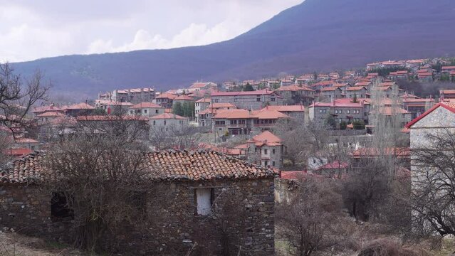 Mountain Lodges traditional village settlement with stone-built houses and red tile rooftops in Agios Athanasios, Greece.