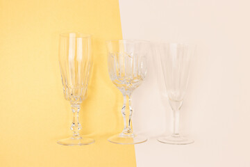 Three vintage crystal glasses on a beige and gold colored background.