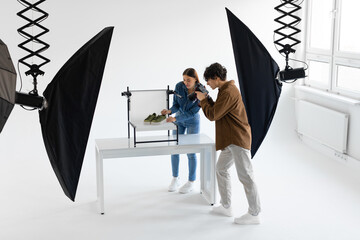 Professional team of photographer and content manager shooting stylish shoes in photostudio, working together