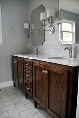 Clean bright bathroom with dark wood vanity and white marble sinks in a new home or after a remodel