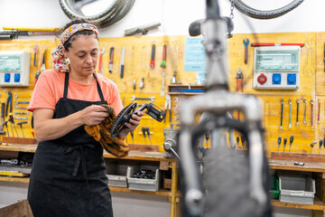 woman cleaning parts she has removed from the bicycle for maintenance and overhaul in a bike shop