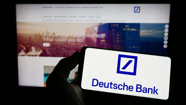 Stuttgart, Germany - 03-25-2023: Person holding smartphone with logo of German financial company Deutsche Bank AG on screen in front of website. Focus on phone display.