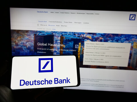 Stuttgart, Germany - 03-25-2023: Person holding mobile phone with logo of German financial company Deutsche Bank AG on screen in front of web page. Focus on phone display.