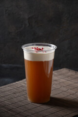 Chinese cheese tea in plastic cup with whipped cream cheese topped berries on black background. Vertical format. Asian cuisine and local food.
