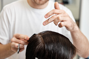 Fototapeta premium Barber talking to caucasian man while sitting in chair