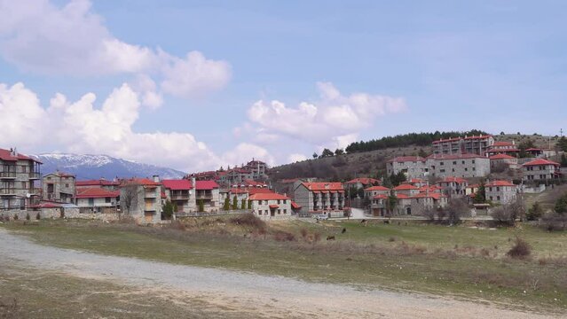 Mountain Lodges traditional village settlement with stone-built houses and red tile rooftops in Agios Athanasios, Greece.