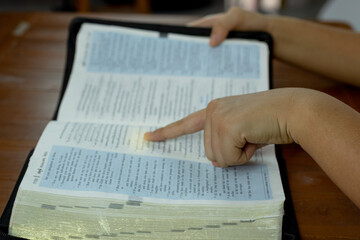Close-up of Prayer hand pointing to the Bible Spiritual book, concepts by studying the Holy Scriptures
